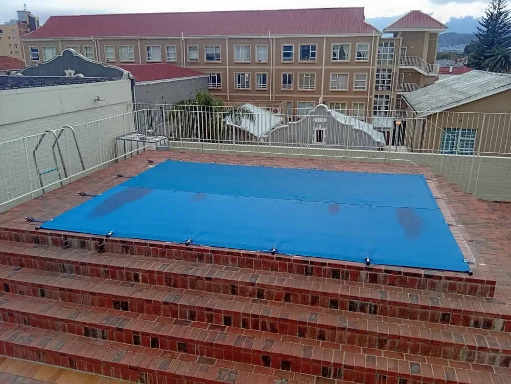 Rooftop pool cover cut to fit around the ladder